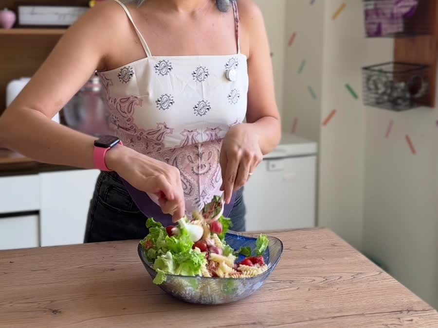 Mezclando la ensalada de pasta con la lechuga en un bowl grande