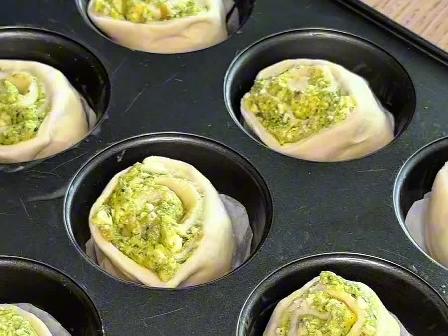 Los rollos de pesto acomodados en el molde de muffins antes de leudar