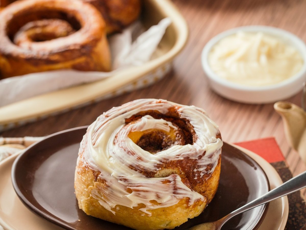 Rollo de canela con glaseado, servido con tenedor y café